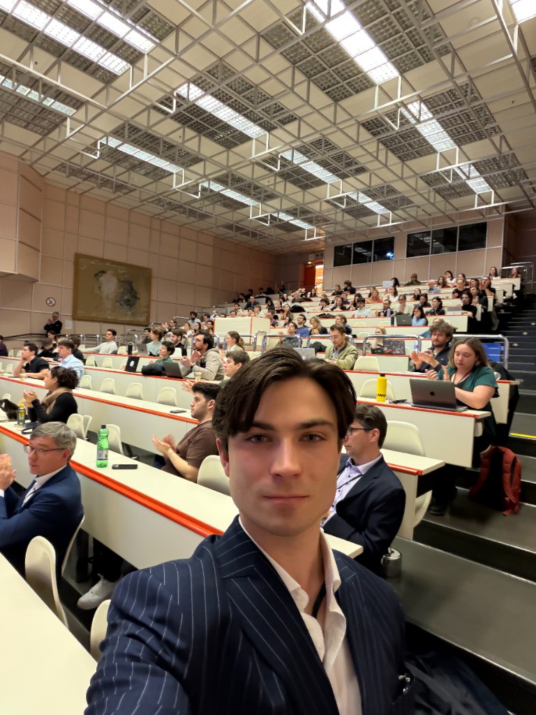 Constantin in a suit, in front of a university lecture hall